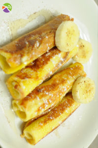 Une recette de pains perdus roulés à la banane, accompagnée de miel et du sucre glace.